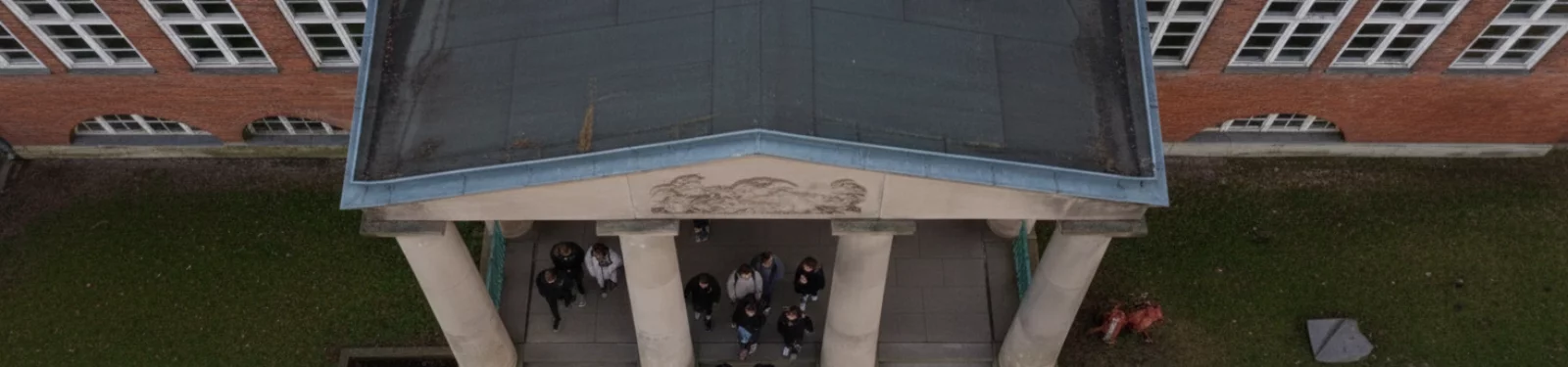 Fahrschule am Schadow-Gymnasium in Berlin-Zehlendorf – Luftaufnahme des Schuleingangs mit Säulen und Treffpunkt für Fahrschüler