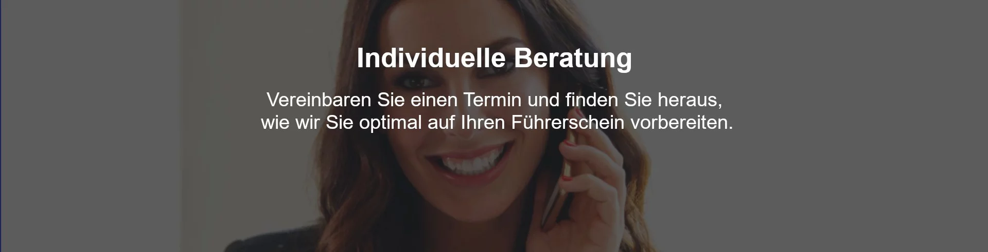 Junge Frau mit einem Telefonhörer in der Hand sitzt lächelnd an einem Schreibtisch.