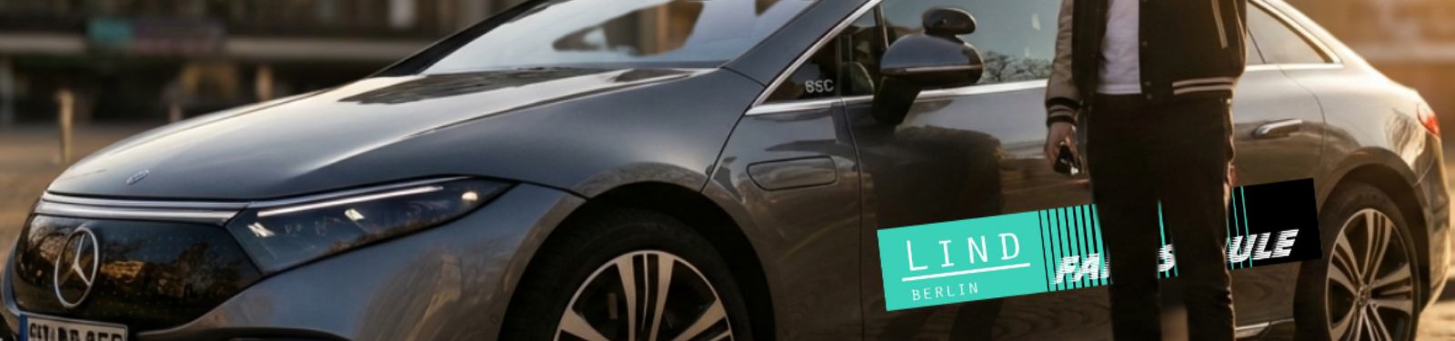 ein EQE der Fahrschule Lind steht vor dem Bierpinsel mit dem Auto, davor ein Fahrschüler