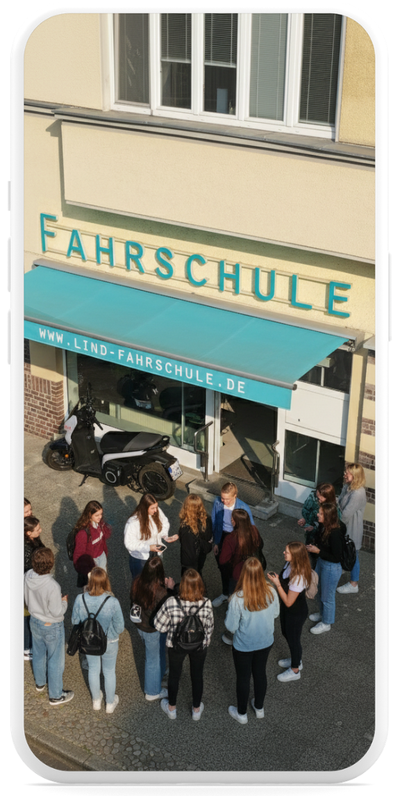Das Bild zeigt viele Fahrschüler aus Sicht einer Drohnenaufnahme vor dem Eingang der Fahrschule Lind