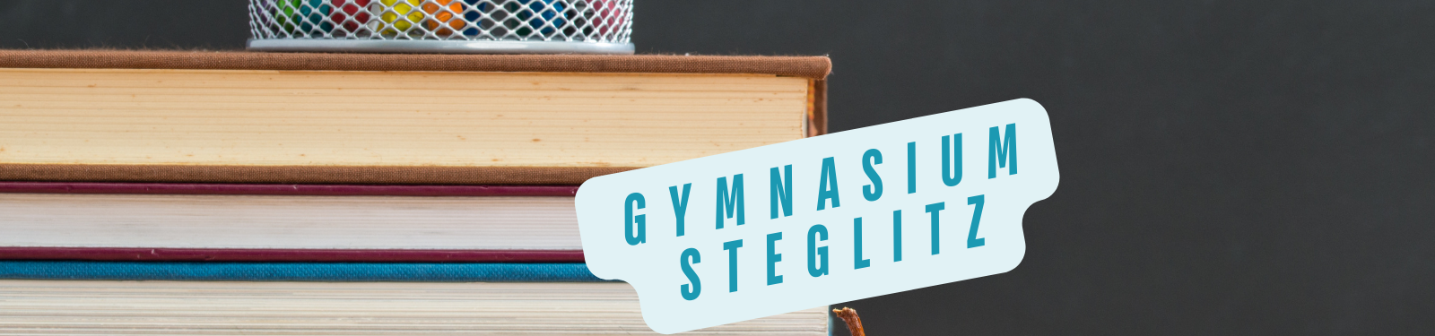 Bücherstapel mit einem Namensschild 'Dreilindengymnasium' in türkisfarbener Schrift.
