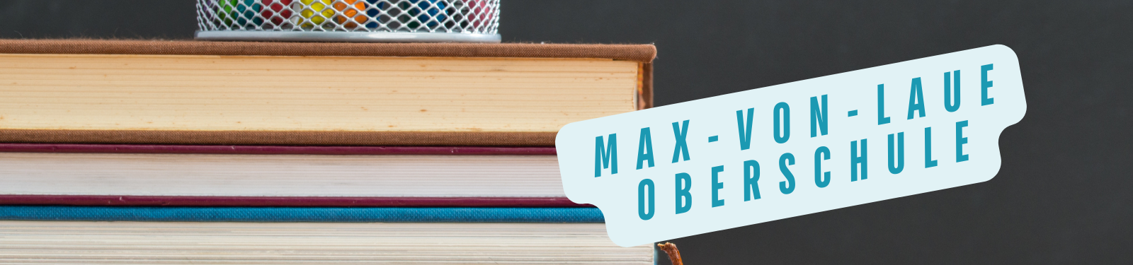 Stapel Bücher mit einem Schild, auf dem 'Max-von-Laue-Oberschule' steht. Symbolbild für Bildung und Schule.