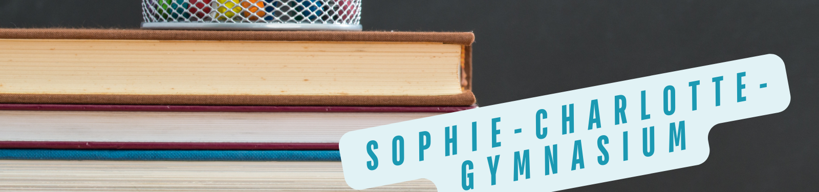 Stapel Bücher mit einem Schild, auf dem "Sophie-Charlotte-Gymnasium" steht.