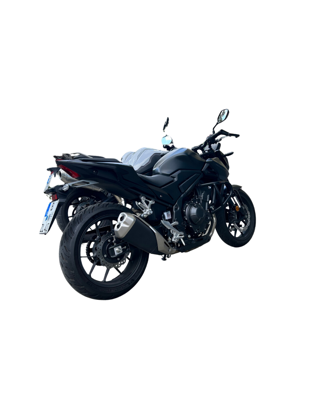 Das Bild zeigt ein modernes, schwarzes Motorrad aus der Flotte der Fahrschule Lind. Das Motorrad steht seitlich, sodass der Hinterreifen und die Auspuffanlage gut sichtbar sind. Die Maschine wirkt sportlich und robust – perfekt für die Fahrschüler, die das Fahren auf zwei Rädern erlernen wollen. Im Hintergrund ist ein weiteres Motorrad zu erkennen. Das Design strahlt eine Mischung aus Dynamik und Eleganz aus, passend für ein motivierendes Fahrerlebnis.